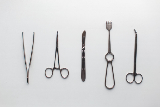 Instrumenty chirurgiczne (pęsety, szczypce, zacisk ostrza, Skalpel, nożyczki) na białym stole. - Zdjęcie, obraz
