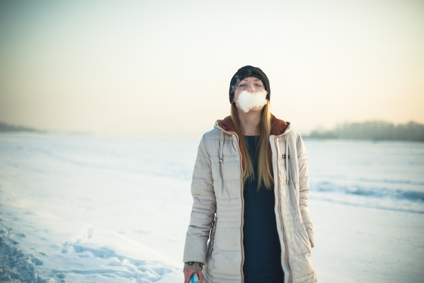 girl in mask smokes an electronic cigarette - 写真・画像