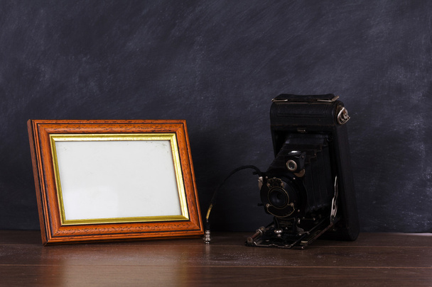 Vintage camera and frame against blackboard background - Photo, Image