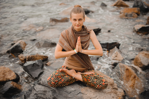 Woman meditating at the beach . yoga retreat. namaste in lotus pose - Fotó, kép