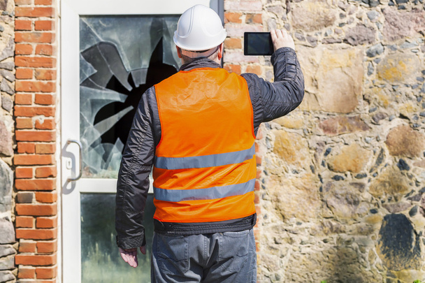 Stavební inspektor s počítačem tablet Pc poblíž rozbité okno  - Fotografie, Obrázek