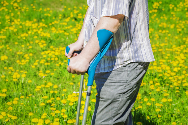 Hombre discapacitado con muletas en el campo de diente de león en verano
  - Foto, imagen