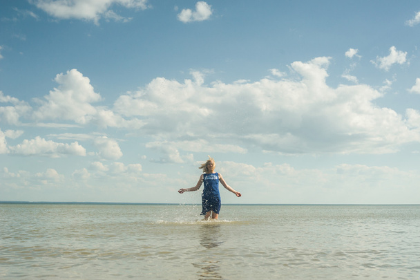 girl in a dress jumping in sea water - Фото, изображение