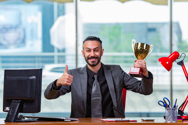Empresario ganando trofeo de copa en la oficina
 - Foto, Imagen