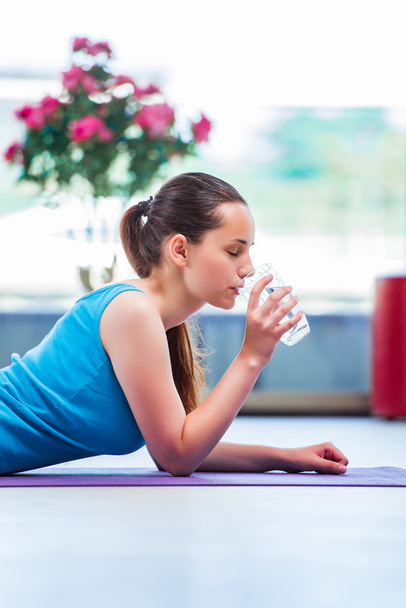 Young woman drinking water in gym health concept - Фото, изображение
