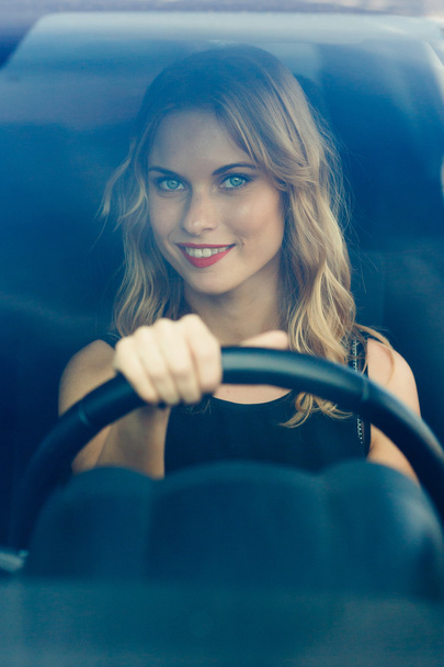 Smiling woman behind the wheel of car, vertical composition - Foto, afbeelding