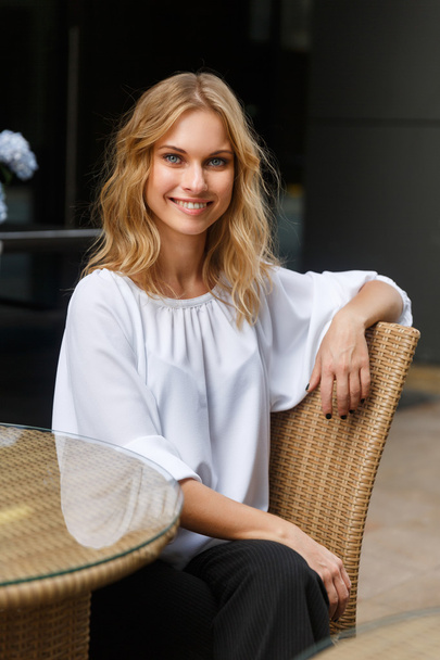 Young smiling blonde woman sitting cross-legged at coffee table - Фото, зображення