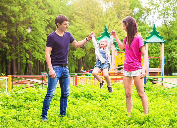 lachende hübsche Mädchen springt mit Eltern - Foto, Bild