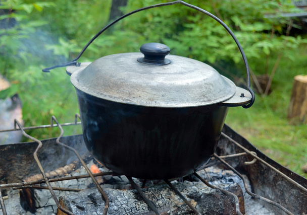 Olla de hierro fundido con tapa para cocinar sobre fuego abierto
. - Foto, Imagen