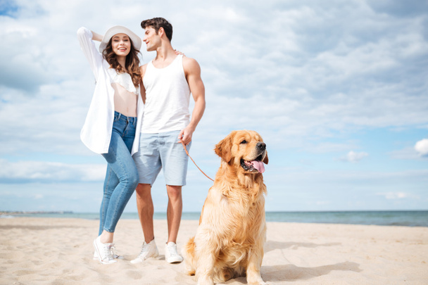 Couple and their dog standing on the beach - 写真・画像