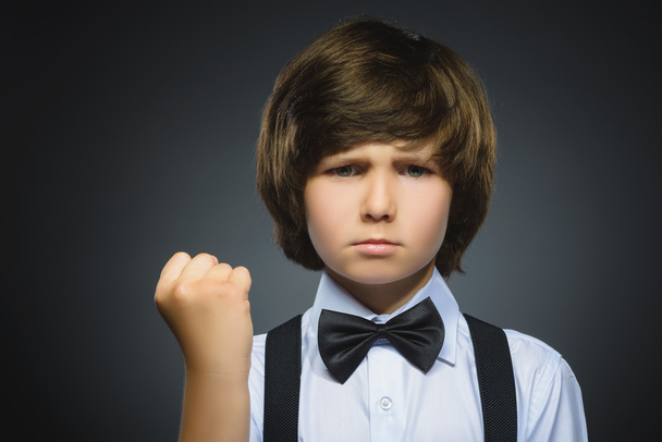 Portrait of angry boy isolated on gray background. He raised his fist to strike. Closeup - Foto, imagen