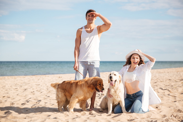 Young beautiful couple standing on the sea shore with dog - Fotografie, Obrázek