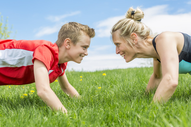 Happy son and mother are doing exercises in the summer park - Fotografie, Obrázek