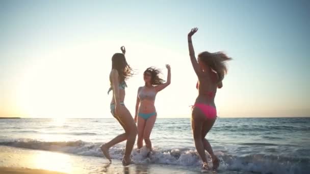 vrolijke meisjes in badmode plezier op het strand slow motion - Video