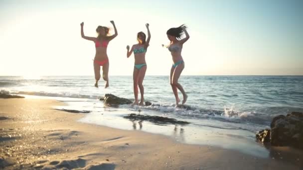Три счастливые девушки в бикини прыгают в замедленной съемке на берегу моря
 - Кадры, видео