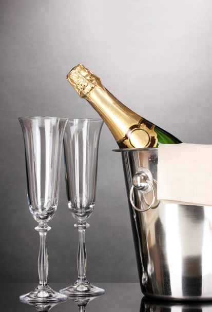 Garrafa de champanhe em balde com gelo e óculos em fundo cinza
 - Foto, Imagem