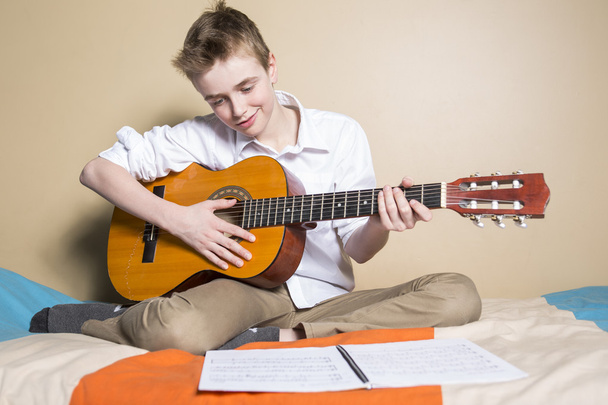 teenage boy playing guitar in her bedroom - Fotó, kép