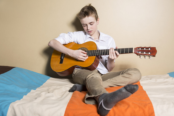 teenage boy playing guitar in her bedroom - Fotografie, Obrázek