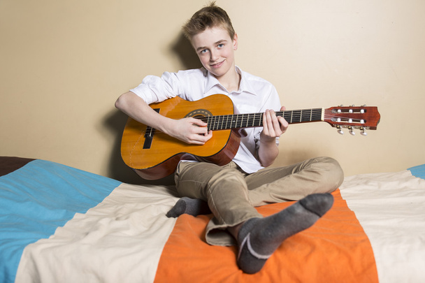 teenage boy playing guitar in her bedroom - Фото, изображение