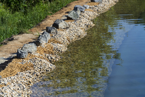 Pedras no banco de lagoa de natação natural ou piscina NSP
 - Foto, Imagem