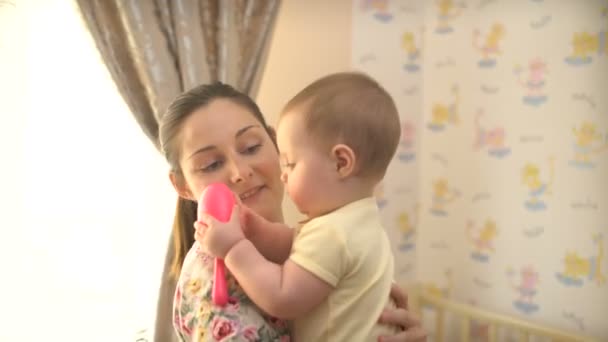 Young happy mother holds a baby in her childrens room - Footage, Video