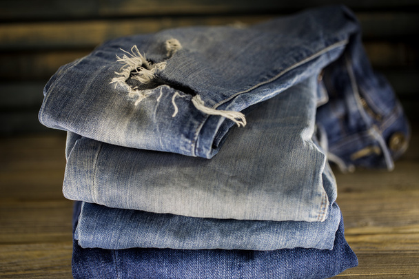 verschillende jeans gevouwen op een houten achtergrond - Foto, afbeelding