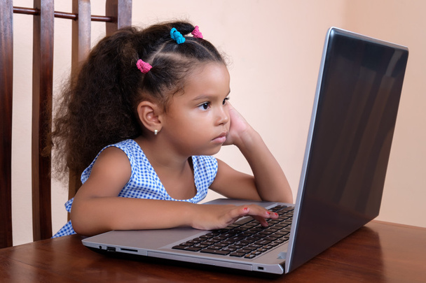 Multiracial small girl using a laptop computer at home - Фото, изображение