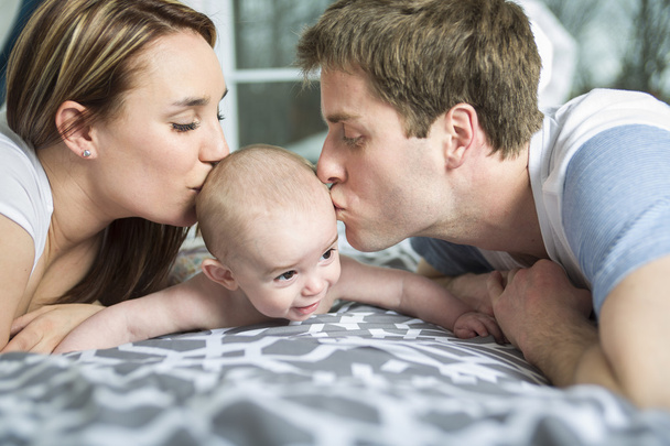 happy family of father, mother and baby playing in bed - Valokuva, kuva