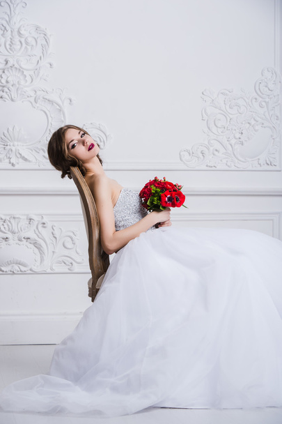 Sluit portret van mooie lachende bruid vrouw met lang krullend haar poseren in trouwjurk op interieur en lachend. Indoor portret van schoonheid. - Foto, afbeelding