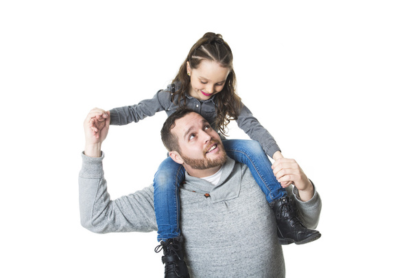 Father carrying daughter on his shoulders, studio shot - Foto, imagen