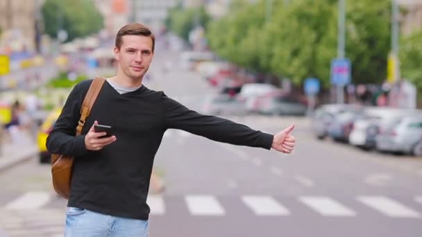 Giovane uomo felice prendere un taxi nelle strade europee. Ritratto di turista caucasico con zaino sorridente e prendere un taxi
 - Filmati, video