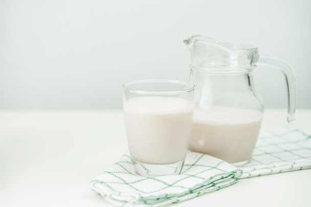 Milk in a glass jug and glass on wooden background - Photo, Image
