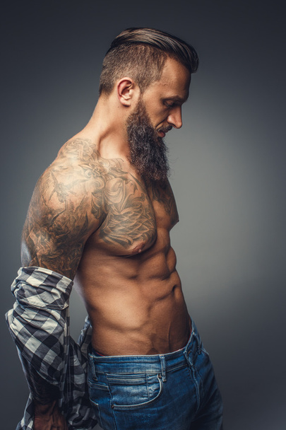 Tattooed male taking off his shirt - Фото, изображение