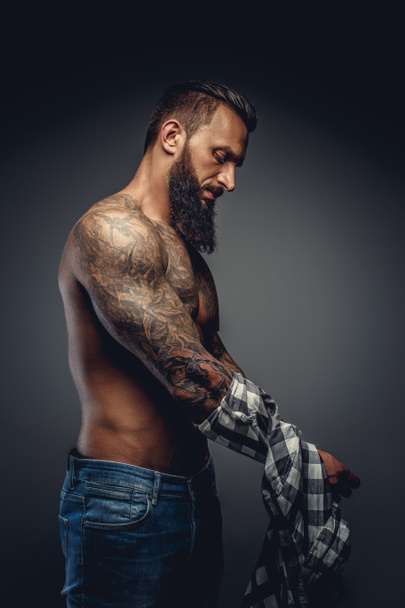Tattooed male taking off his shirt - Photo, Image
