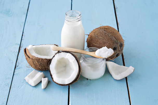 kokosové ořechy s kokosovým mlékem a olejem na modrý stůl - Fotografie, Obrázek