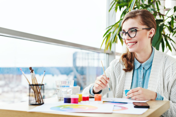 Chica con gafas sentado con pinturas de colores
 - Foto, Imagen