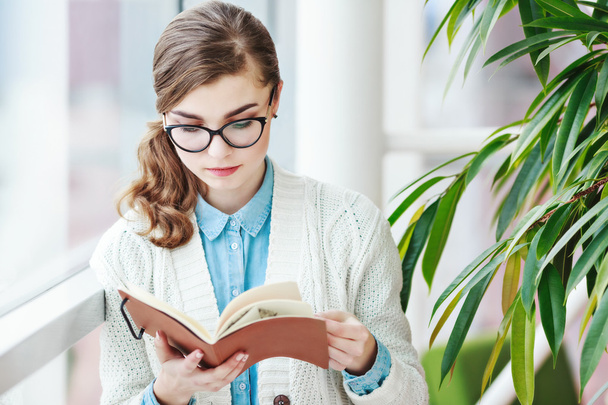 Lovely girl with glasses standing with notebook - Фото, изображение