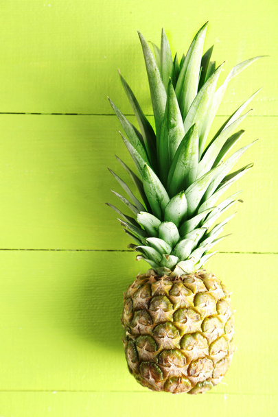 Ripe pineapple on a green background - Фото, изображение