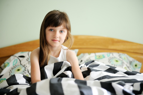 Portrait of awaken little girl sitting in bed - Foto, imagen