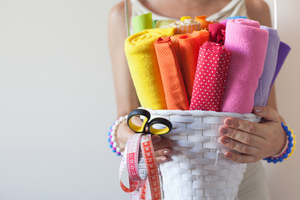 Uma mulher segura tecidos coloridos brilhantes para costura e tesoura
. - Foto, Imagem