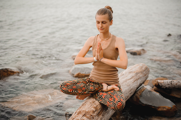 Woman meditating at the beach . yoga retreat. namaste in lotus pose - Foto, afbeelding