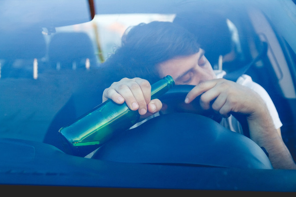 ein Mann am Steuer eines Autos mit einer Flasche Bier - Foto, Bild