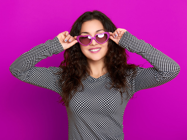 young woman beautiful portrait, posing on purple background, long curly hair, sunglasses in heart shape, glamour concept - Photo, Image