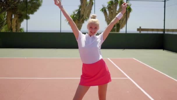 Nainen poseeraa tennismailan kanssa hovissa
 - Materiaali, video