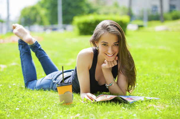 Young woman reading magazine lying on grass - Foto, Bild