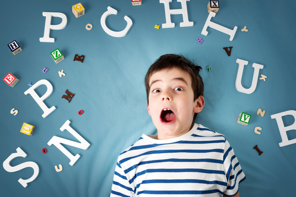 seven years old child lying with letters - Фото, изображение