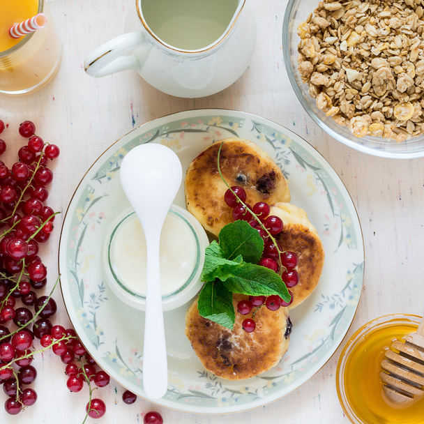 Healthy breakfast: cheesecakes, muesli, yogurt, honey, fresh berries and juice  - Fotoğraf, Görsel