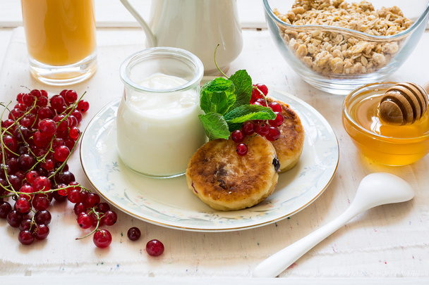Petit déjeuner sain : gâteaux au fromage, muesli, yaourt, miel, baies fraîches et jus de fruits
  - Photo, image