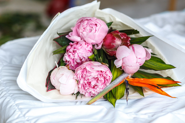 Bouquet of peonies in kraft paper on bed - Zdjęcie, obraz