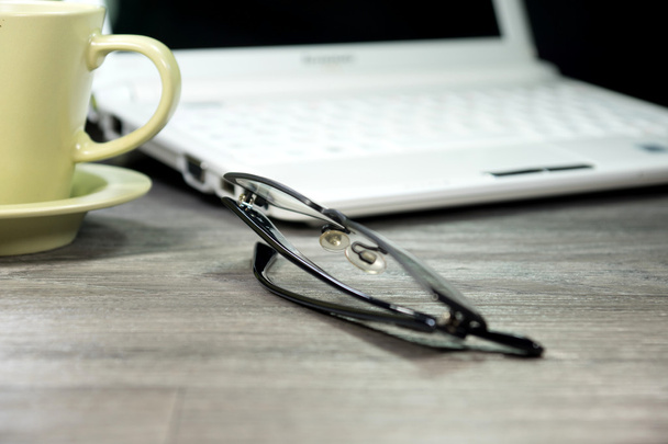 Un portátil y gafas de lectura en una mesa en la oficina
 - Foto, imagen